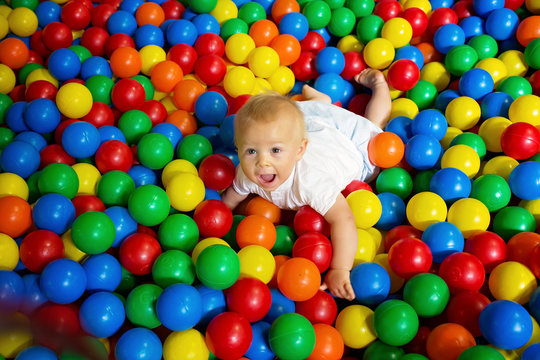Cute toddler boy, child, playing in colorful balls in children playground