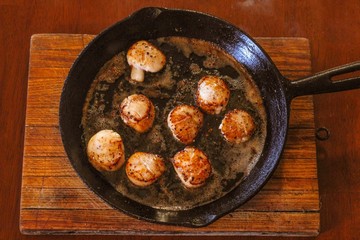 Selective Focus closeup of perfectly seared fresh sea scallops in butter and cracked pepper, sizzling on a cast iron skillet