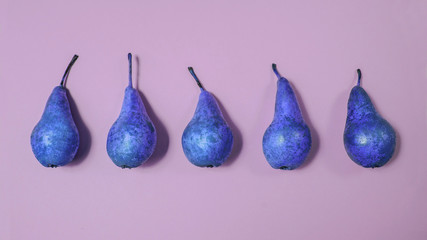 Row of blue pears on pink background. From top view, minimal food creative concept