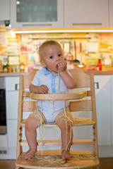 Little baby boy, toddler child, eating spaghetti for lunch and making a mess