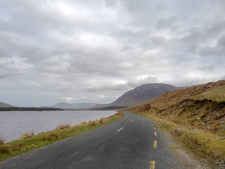 Small road in Connemara National park, Ireland, Cloudy sky. Mountain in the background.