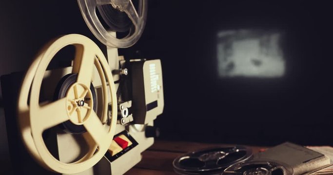 retro 8mm film projector showing movie on the wall in dark room