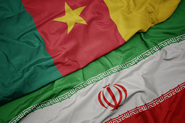 waving colorful flag of iran and national flag of cameroon.