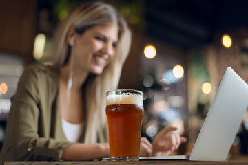 Close up of unrecognizable  happy woman working on her computer while relaxing in a bar.