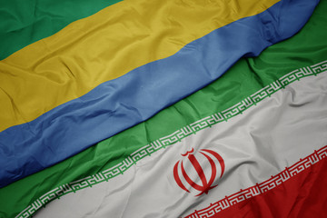 waving colorful flag of iran and national flag of gabon.