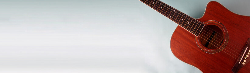 Obraz premium Acoustic guitar resting against a blank blue background with copy space.