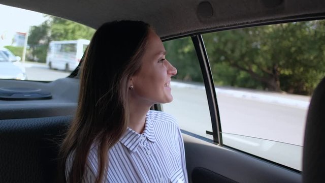 Cute brunette girl rides in taxi in backseat enjoying the ride. 4k.
