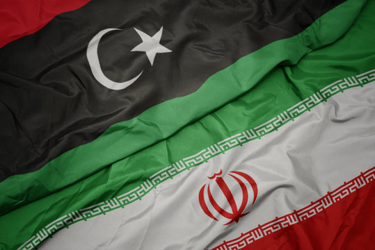 waving colorful flag of iran and national flag of libya.
