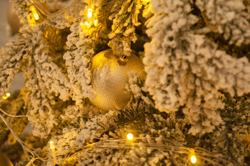 Christmas ball and garland on the Christmas tree. the garland shines with a golden, yellow warm light. Christmas, Christmas background for cards, greetings.