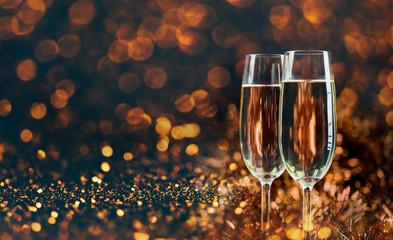 Two champagne glasses over golden bokeh background.