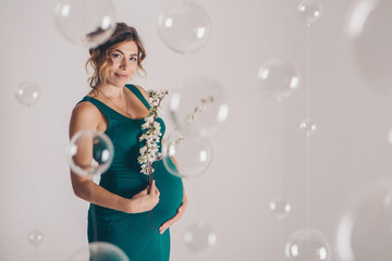 the pregnant woman in green dress thought on white background. The concept of healthy digestion, lifestyle, IVF