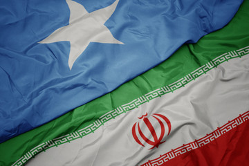 waving colorful flag of iran and national flag of somalia. © luzitanija