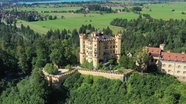 Aerial view of Hohenschwangau Castle in summer, picturesque palace in Bavarian Alps mountains, lush green hills - landscape panorama of Bavaria from above, Germany, Europe