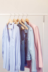 Collection of clothes hanging on rack near white wall. Clothes for women in pastel colors. Office Style.