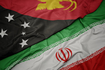 waving colorful flag of iran and national flag of Papua New Guinea .