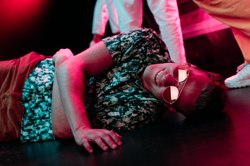 sick man in sunglasses lying on floor in nightclub