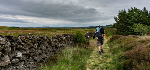 Man with lot's of things on his backpack walking in the highlands