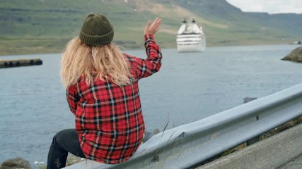 Young woman sits in port watch cruise ship leave