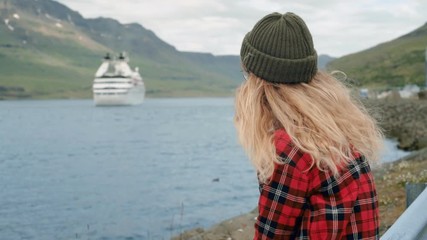 Young woman sits in port watch cruise ship leave