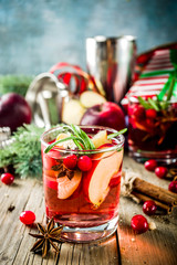 Winter hot sangria cocktail with red apples, wine, cranberry, rosemary and spices, christmas wooden...