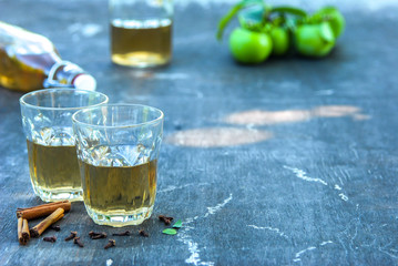 A close-up photo of an apple cider. Vintage glass bottles filled with apple cider vinegar, with glasses on the table. Summer holiday concept