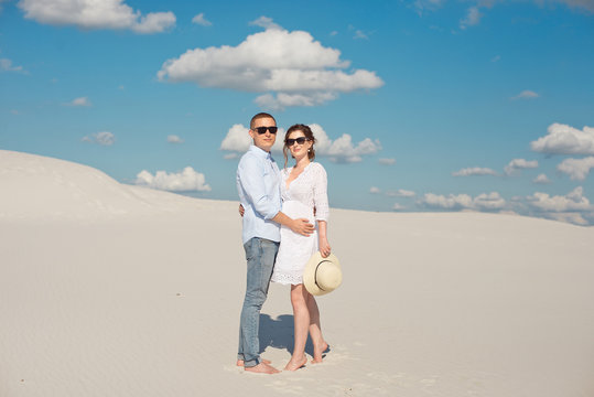 Young couple enjoying the sunset in the dunes. Romantic traveler walks in the desert. Adventure travel lifestyle concept.