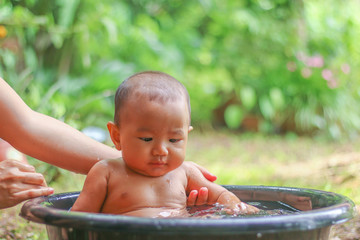 Asian baby in Bathtub  with her mother in the garden.