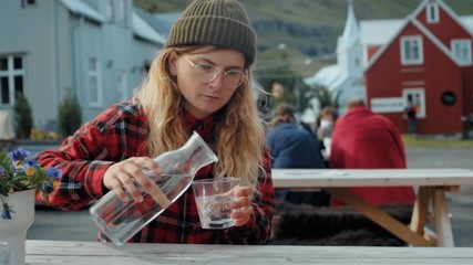 Woman in hipster outfit pour water on terrace