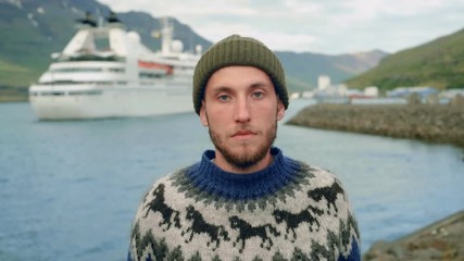 Hipster bearded man in sweater next to cruise ship