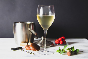 Close-up of glass of white wine on white wooden background.