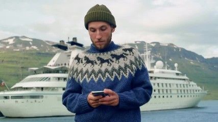 Hipster bearded man in sweater next to cruise ship