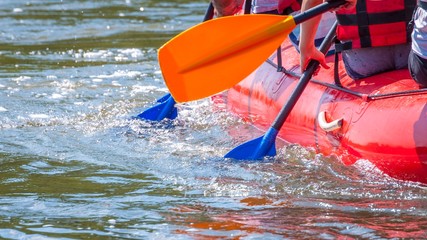 Rafting trip. Close up view of oars with splashes of water. Rowers make an effort to overcome the...