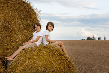 Naklejka na ściany i meble Happy children, playing on haystacks summertime