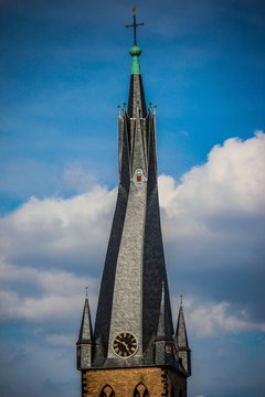 twisted rooftop of a church with a clock 