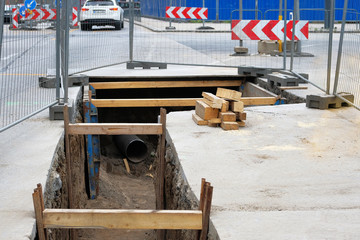 Engineering works. Repair of urban underground communications. Utility infrastructure. Deep hole for pipe laying. Underground pipe installation.