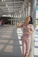 Healthy middle-aged women look happy wearing pink pants outdoor ambience with modern communication tools, tablet.