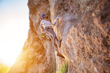 Rock climber is looking up with helmet, rope and carabiners on a sunny summer afternoon