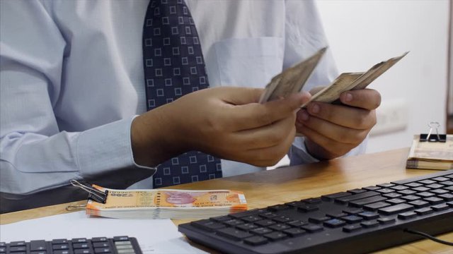 Bank cashier counting Rupee 500 Indian currency notes before handing it over to the customer. 