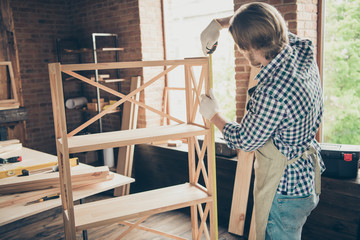 Profile side view of his he nice handsome skilled guy artisan woodworker wearing checked shirt uniform measuring making shelf at industrial brick loft style interior studio