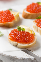 Red caviar on baguette toast with butter, appetizer for wine, champagne. Holiday, new year, Christmas, buffet. Delicious canape, food