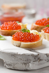 Red caviar on baguette toast with butter, appetizer for wine, champagne. Holiday, new year, Christmas, buffet. Delicious canape, food