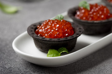 Red caviar in tartlets black, appetizer wine, champagne. Holiday, new year, Christmas, buffet. Delicious canape, food