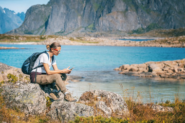 Naklejka na ściany i meble Woman traveler in Norway, on mountains in the Lofoten islands with a phone in his hand exploring the map