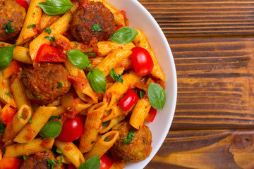 Italian penne pasta with meatballs and tomatoes