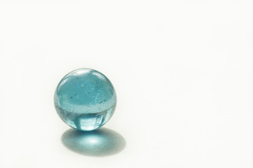 Glass ball of blue color on a white background. Copy space. Abstract background. Shallow depth of field (DOF)