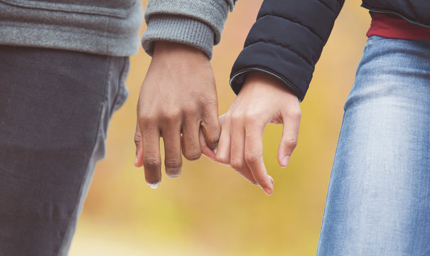 Couple holding hands, walking in park, closeup
