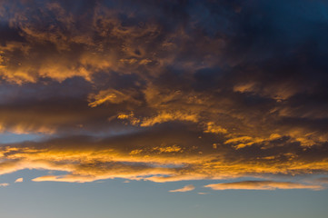 Dramatischer Wolkenhimmel mit dunklen Regenwolken und hellen Wolken die von der tiefstehenden Sonne angestrahlt stimmungsvoll im Abendrot leuchten vor und nach einem Gewitter im sonst  grauen November