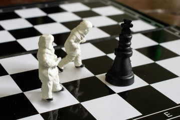 Business strategy. Miniature businessman standing on chessboard with chess pieces.