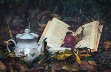 Cup of hot tea, old books and fallen autumn leaves	