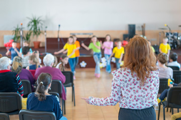 Performance by talented children. Children on stage perform in front of parents. image of blur kid 's show on stage at school , for background usage. Blurry